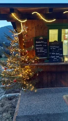 Steffi´s Hütte am Ried Farchant Geschmückter Tannenbaum vor uriger Hütte mit Preistafeln für Speisen und Getränke