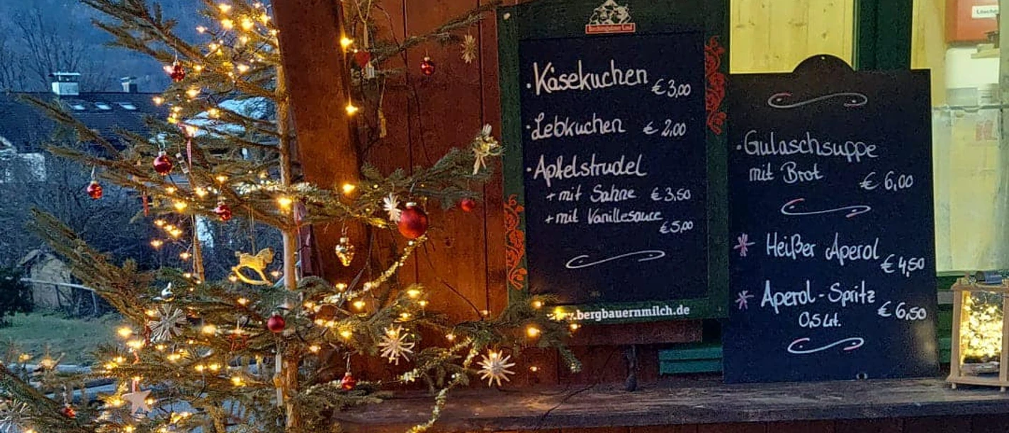 Steffi´s Hütte am Ried Farchant Geschmückter Tannenbaum vor uriger Hütte mit Preistafeln für Speisen und Getränke