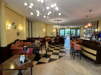 Gemütliches Café mit moderner Beleuchtung, stilvollen Sitzbereichen und großen Fenstern im Hintergrund.