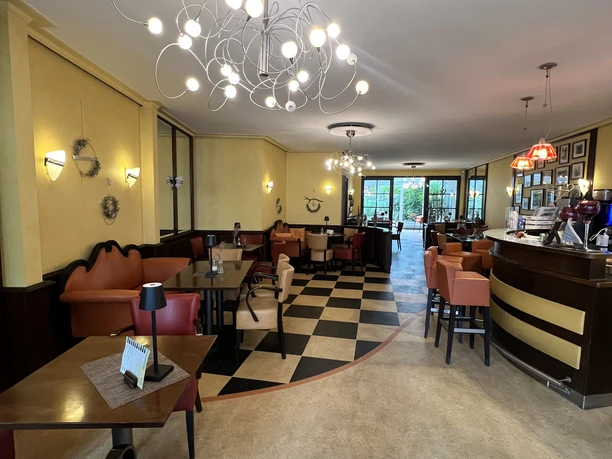 Gemütliches Café mit moderner Beleuchtung, stilvollen Sitzbereichen und großen Fenstern im Hintergrund.