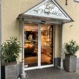 Vorbohle 2 Eingangsbereich eines Cafés mit gläserner Tür, dekoriert mit Pflanzen in modernen Kübeln.