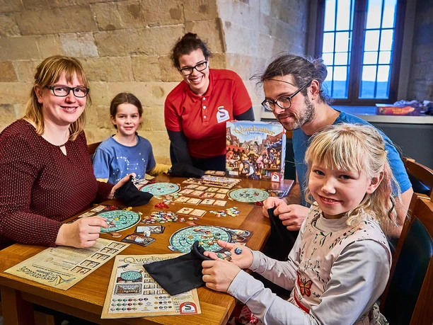 Spieletag Festung Königstein Menschen unterschiedlichen Alters spielen gemeinsam Brettspiele in einem gemütlichen Raum mit Steinwänden.