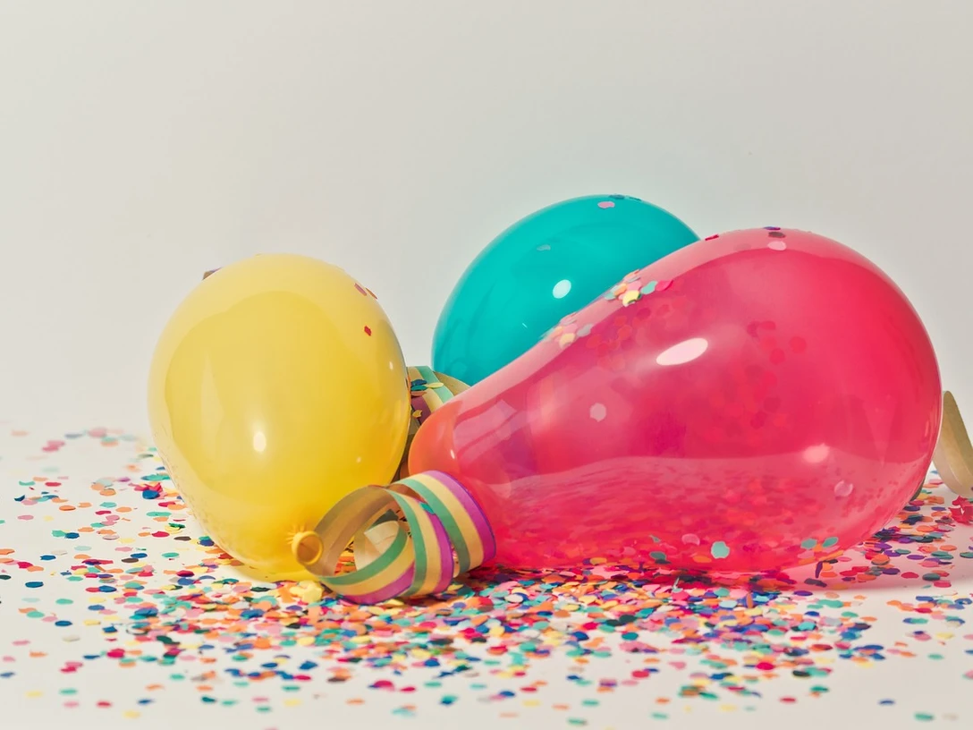 Karnevalsparty Bunte, mit Konfetti übersäte Luftballons auf hellem Hintergrund, die eine fröhliche Feier andeuten.