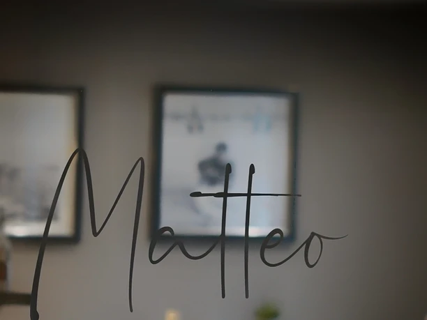 Matteo-Pizza-Pasta-Vino.jpg Blick in ein elegantes Restaurant mit dem Schriftzug "Matteo Pizza Pasta Vino" auf Glas.