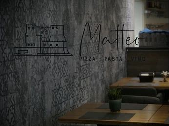 Das Bild zeigt ein gemütliches italienisches Restaurant mit Holztischen und stilvoller Wandgestaltung.