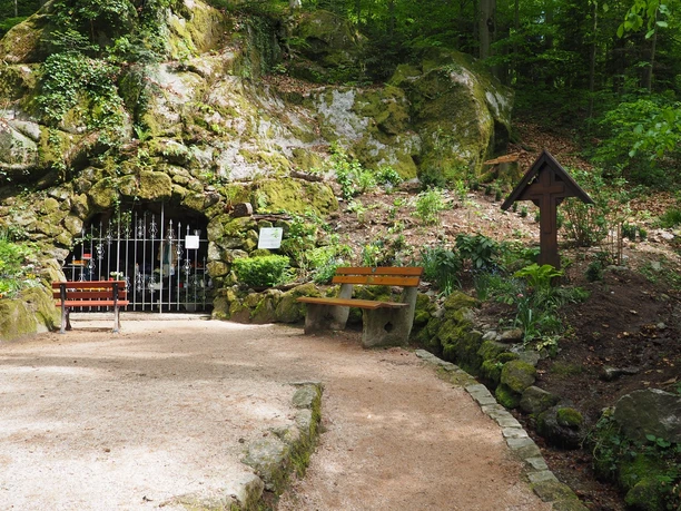 Blick auf Lourdesgrotte mit Bänken davor zum verweilen.