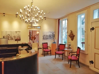 Rezeption eines Hotels mit großen Fenstern, eleganter Beleuchtung und roten Sitzmöbeln.