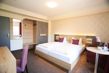 Helles Hotelzimmer mit zwei Einzelbetten, künstlerischer Beleuchtung und modernen Möbeln.