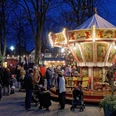 ._Weihnachtsmarkt_MWoestheinrich.jpg Ein nostalgisches Karussell dreht sich inmitten einer Menschenmenge auf einem stimmungsvollen Abendmarkt.