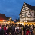 Nikolausmarkt Hövelhof Menschenmenge besucht abendlichen Nikolausmarkt mit Fachwerkhäusern und festlich beleuchteten Ständen.