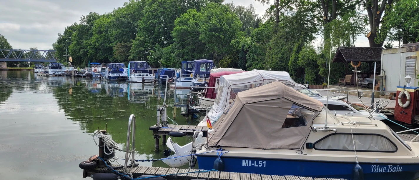 Hafen Getmold Boote am Hafen Getmold, umgeben von grünen Bäumen und ruhigem Wasser, Bootssteg linksseitig belegt.