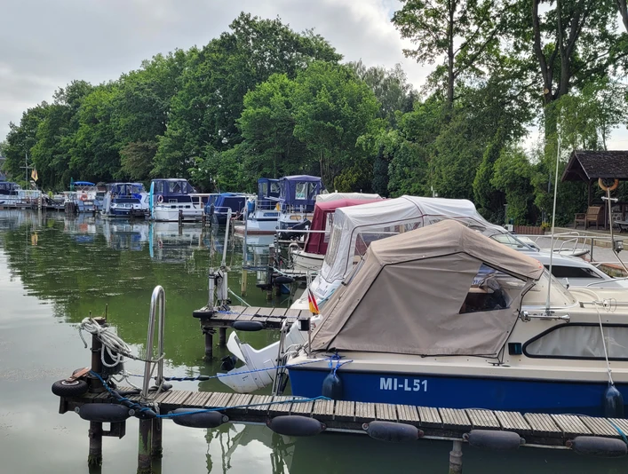 Hafen Getmold Boote am Hafen Getmold, umgeben von grünen Bäumen und ruhigem Wasser, Bootssteg linksseitig belegt.