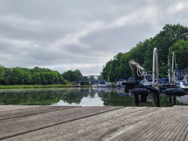 Hafen Getmold Ruhiger Hafen mit Anlegestellen und Booten an einem bewölkten Tag, im Hintergrund eine Brücke.