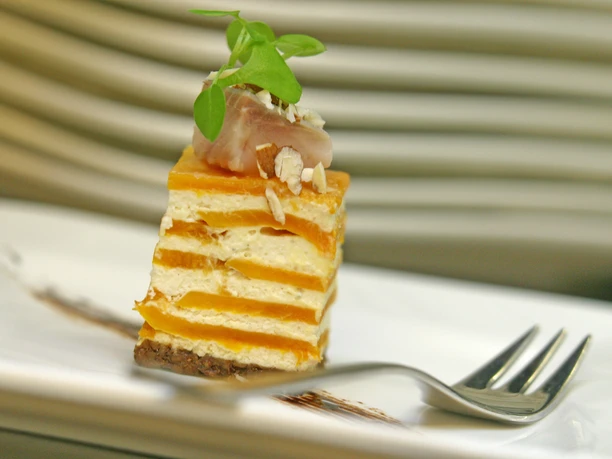 Restaurant Aureus im Hotel Vivendi-Herford (6).jpg Ein kunstvoll angerichtetes Vorspeisengericht präsentiert sich als geschichteter Turm aus Kürbis und Ziegenkäse, mit einer herzhaften Garnitur obenauf.