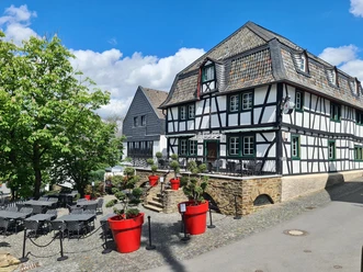 Hotel Von Landsberg Traditionelles Fachwerkhaus mit Schieferdach umgeben von grünen Bäumen, roter Pflanzendekoration.