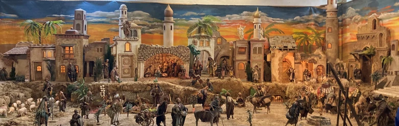 Golfclub Orientalische Krippe Ein kunstvoll detailliertes Krippendorf bei Sonnenuntergang, mit Figuren beim Alltag in einem orientalischen Setting.