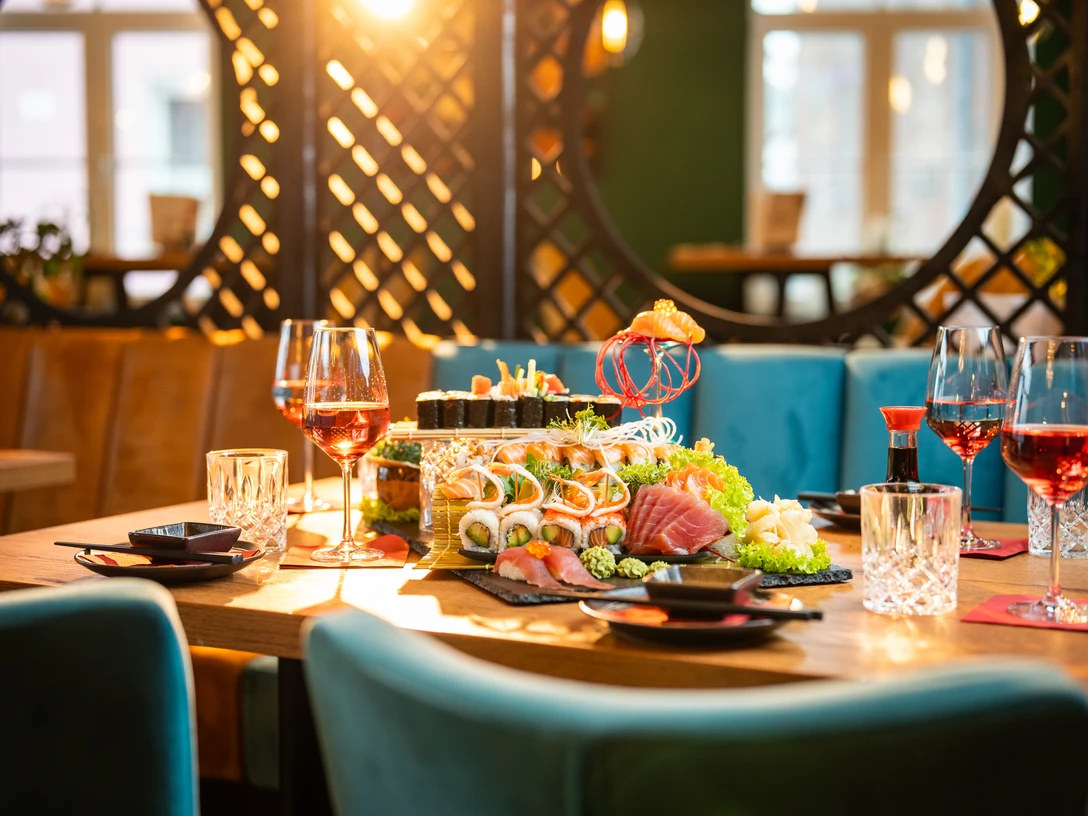 20240117tk-BlueMoon-HighRes-001.jpg Ein festlich gedeckter Tisch mit Sushi, dekoriert mit leuchtenden Farben, in einem eleganten Raum.