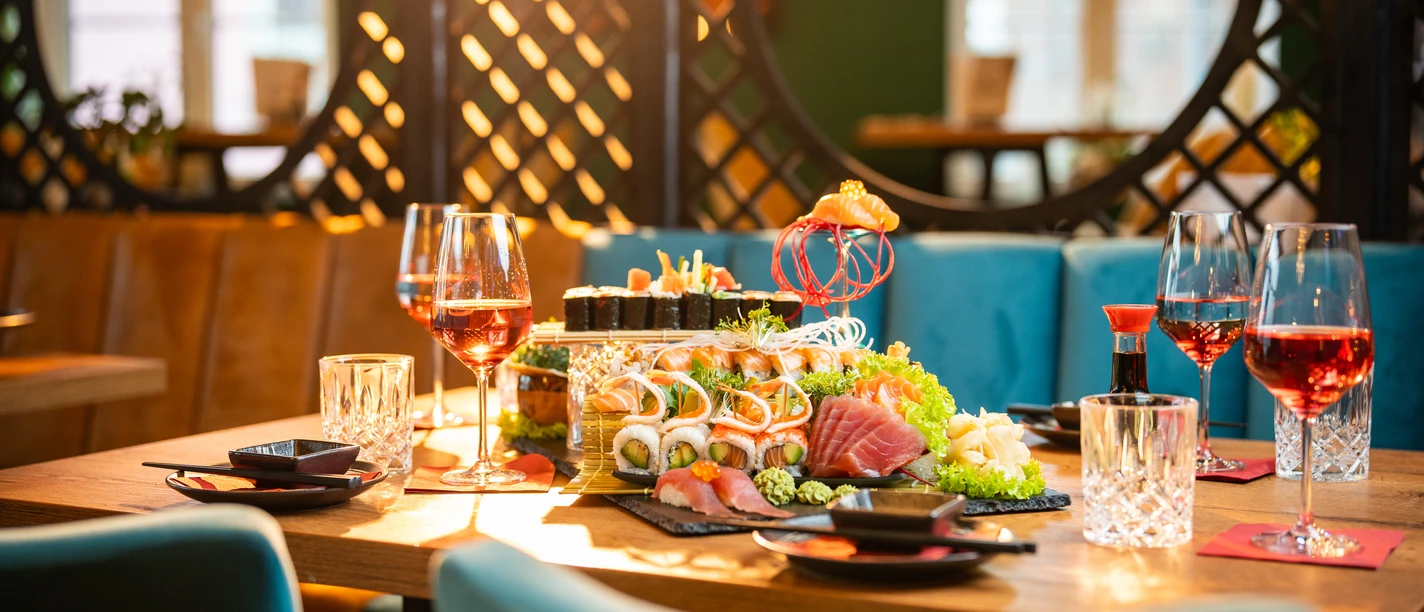 20240117tk-BlueMoon-HighRes-001.jpg Ein festlich gedeckter Tisch mit Sushi, dekoriert mit leuchtenden Farben, in einem eleganten Raum.