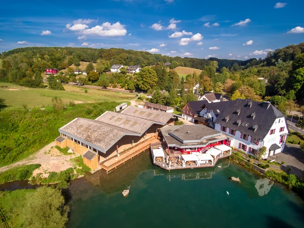 Herrenstrunden 4.png Luftaufnahme zeigt malerische Landschaft in Bergisch Gladbach mit traditionellen Gebäuden und Teich.