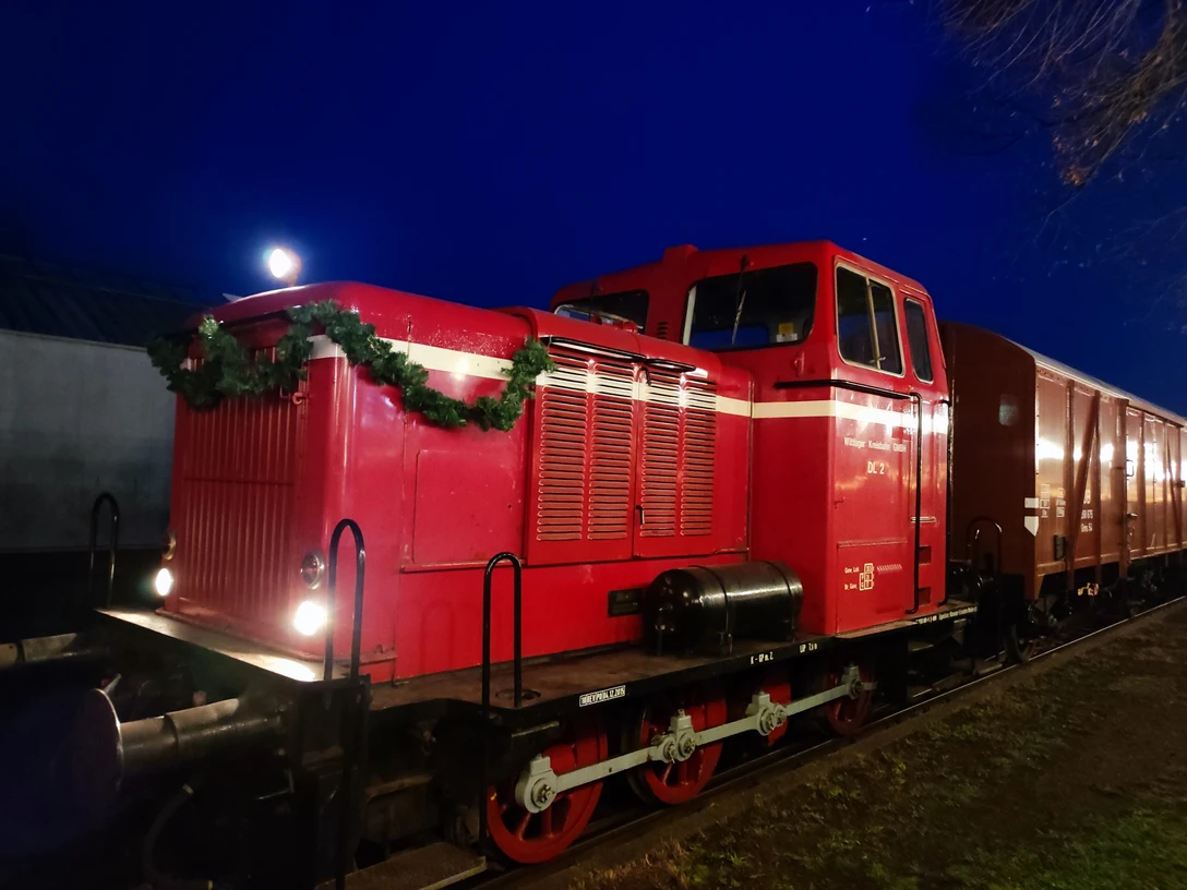 Rote Diesellokomotive der Museumseisenbahn Nikolaus, abends, mit Tannengirlande dekoriert.