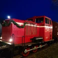 Rote Diesellokomotive der Museumseisenbahn Nikolaus, abends, mit Tannengirlande dekoriert.