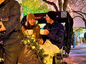 Rikolonia Köln Glühweinfahrt.png Zwei Personen sitzen am Abend hinten in einer Rikscha und trinken GlühweinTwo people sit in the back of a rickshaw in the evening and drink mulled wine