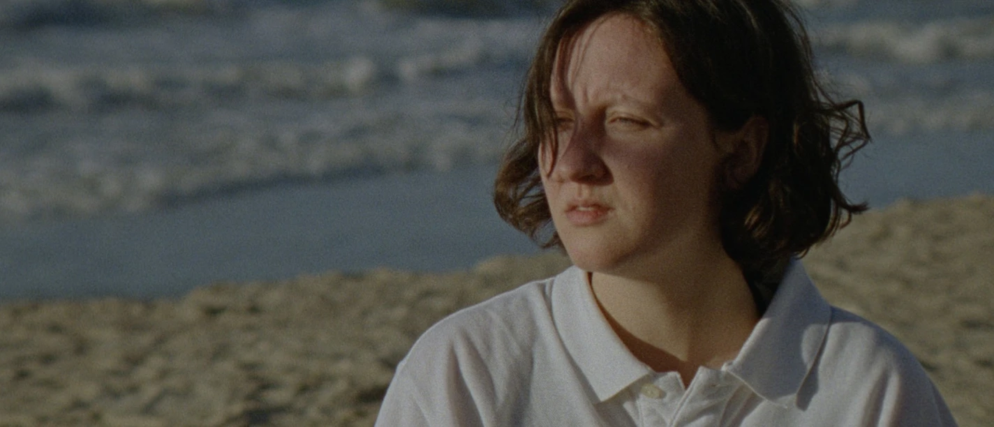 Kurzfilmfestival Frau am Strand, nachdenklich in die Ferne blickend, während die Wellen brechen.