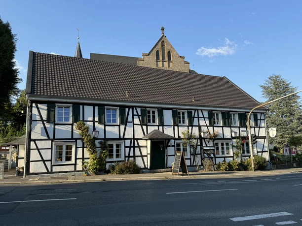 Dürscheider Hof - Außenansicht <p>Fachwerkhaus in Kürten mit Satteldach und gepflegter Fassade unter blauem Himmel.</p>