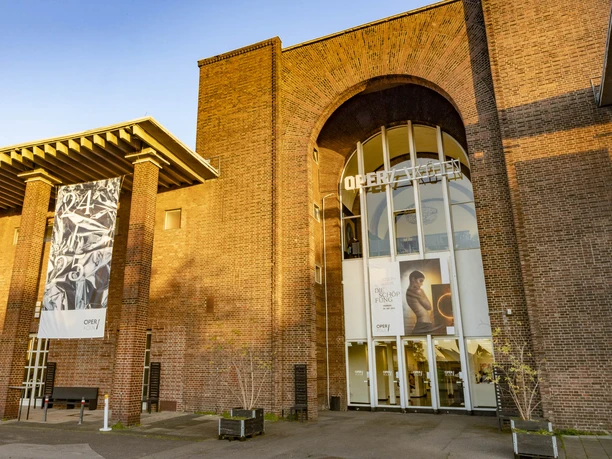 Oper Köln im StaatenHaus Das Bild zeigt die Fassade der Kölner Oper, ein beeindruckendes Gebäude aus Ziegelsteinen.