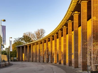 Oper Köln im StaatenHaus Die Abendsonne taucht die rotbraune Backsteinarkade der Kölner Oper in warmen Goldton.The evening sun bathes the reddish-brown brick arcade of the Cologne Opera House in a warm golden hue.