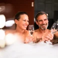 bad-driburg-graeflicher-park-health-resort-hotel-spa-28.jpg Ein Paar genießt gemeinsam ein Glas Sekt in einem sprudelnden Whirlpool, lächelnd und entspannt.