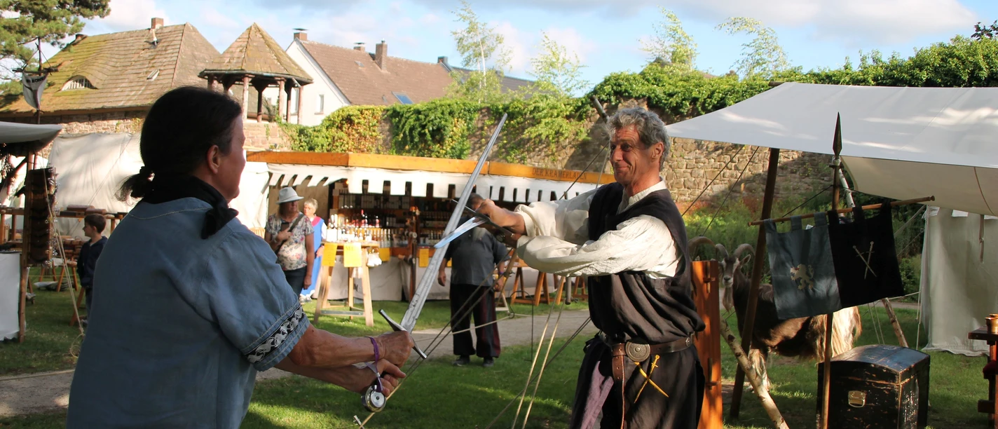 Anno_3_Schwertkampf.jpg Mittelalterliche Stände an der Wallnalage in Höxter mit zwei mittelalterlich gekleideten Schwertkämpfern im Vordergrund