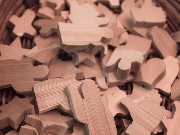 Verschiedene hölzerne Spielzeugformen in einem Korb, darunter Sterne, Figuren und Tiere.