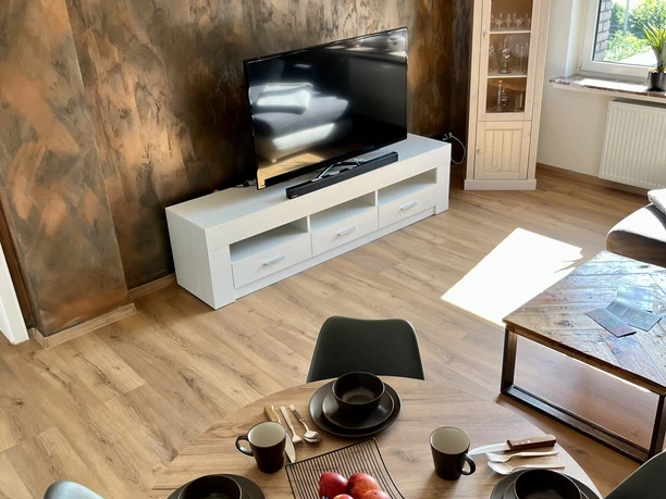 Essbereich der Ferienwohnung im Weserbergland Esstisch aus hochwertigem Holz, im Hintergrund weißes TV-Rack mit Flachbildfernseher
