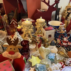 Verschiedene Weihnachtsdekorationen, darunter Engelsfiguren, ein rotes Rentier und festliche Kerzen.