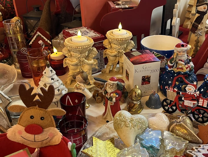 Verschiedene Weihnachtsdekorationen, darunter Engelsfiguren, ein rotes Rentier und festliche Kerzen.