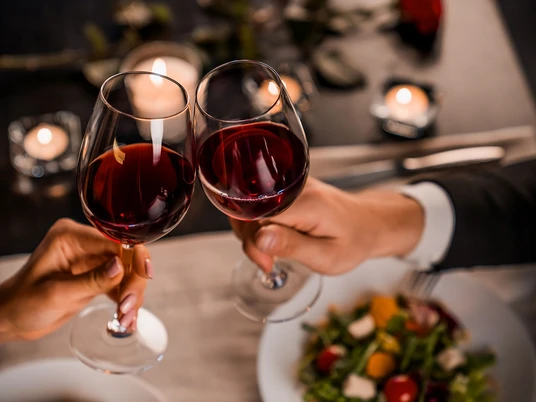 Close up of young couple toasting with glasses of red wine at restaurant Close up of young couple toasting with glasses of red wine at restaurant