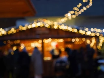 Sülzer Weihnachtsdorf Bunte Lichter vor einem verschwommenen Holzhäuschen auf einem Weihnachtsmarkt in der Dämmerung.Colorful lights in front of a blurred wooden house at a Christmas market at dusk.