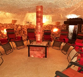 Salzgrotte Innen.jpg Ein Raum mit Entspannungsliegen um einen beleuchteten Salzsteinturm, umgeben von Salzwänden.