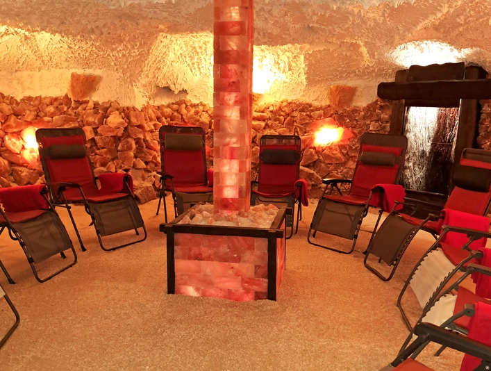 Salzgrotte Innen.jpg Ein Raum mit Entspannungsliegen um einen beleuchteten Salzsteinturm, umgeben von Salzwänden.