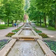 Brunnen im Kneipp-Kurpark Bad Camberg In der Mitte ist ein Kaskadenbrunnen zu sehen, links und rechts davon laufen jeweils zwei Personen.