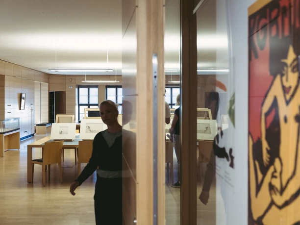 A person in the study room of the Kupferstich-Kabinett Dresden in front of drawings and art posters.