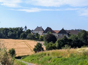 Panoramablick auf Drenke mit einer Kirche und Fachwerkhäusern, umgeben von Feldern und Bäumen.