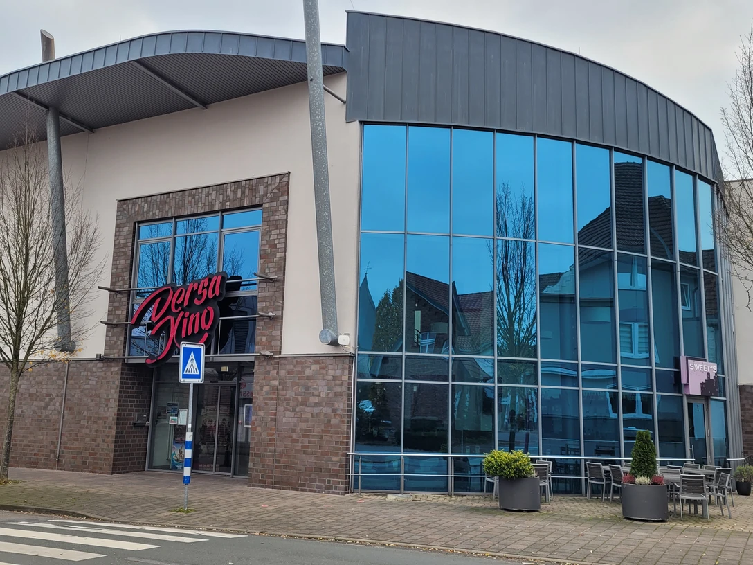 Dersa Kino Rahden mit moderner Glasfassade, Eingangsbereich und Außenbestuhlung vor dem Gebäude.