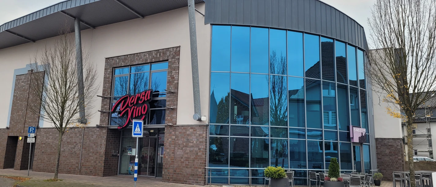 Dersa Kino Rahden mit moderner Glasfassade, Eingangsbereich und Außenbestuhlung vor dem Gebäude.