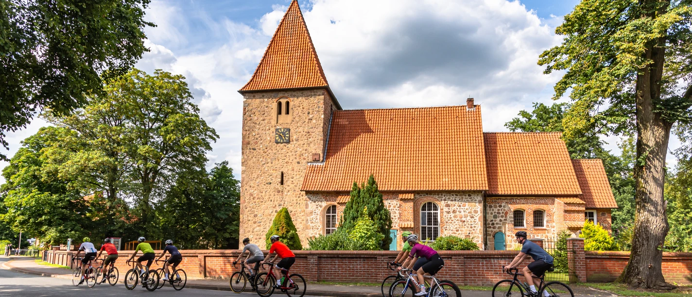Rennradgruppe vor der St. Bartholomäus-Kirche in Kirchwalsede Rennradgruppe vor der St. Bartholomäus-Kirche in Kirchwalsede