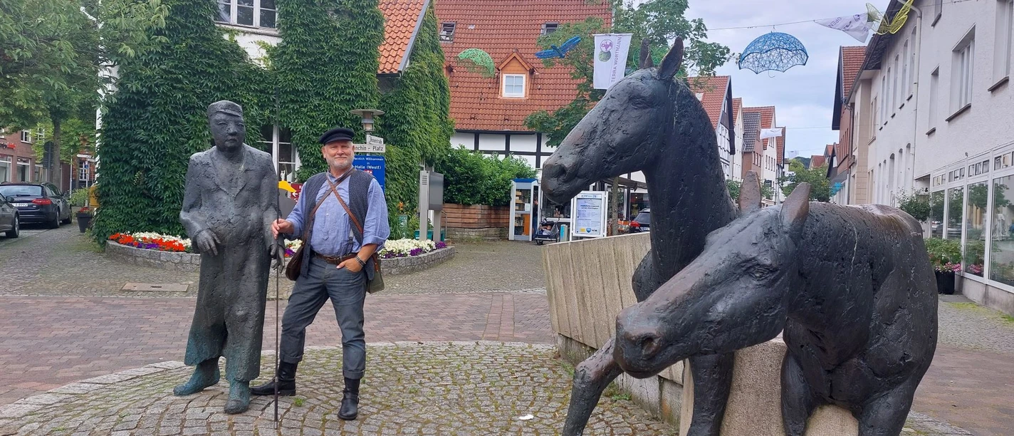 haller_willem.jpg Zwei Bronzeskulpturen in einer gepflasterten Straße zeigen Pferde und Männer bei einer Plauderei.