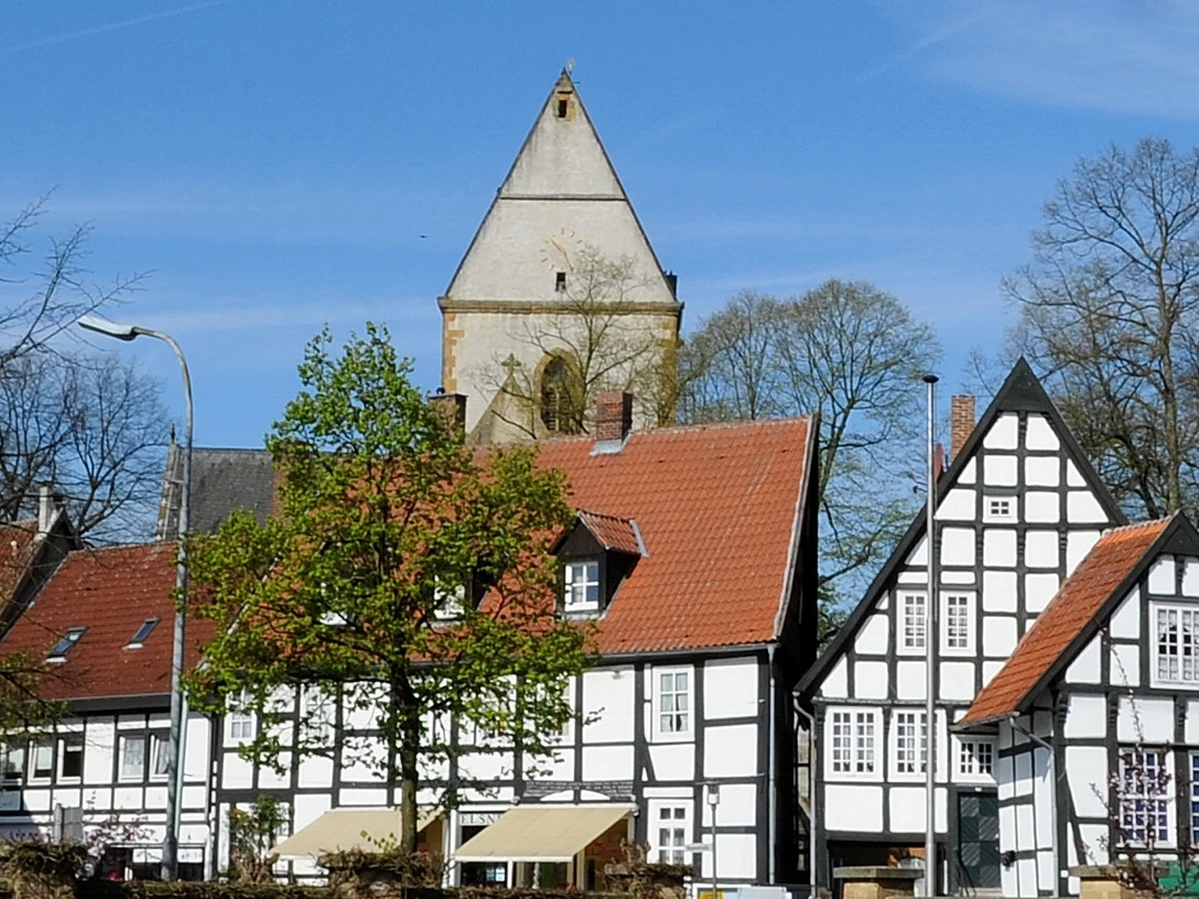 haller_herz1.jpg Historische Fachwerkhäuser mit roten Dächern und einem Kirchturm im Hintergrund unter klarem Himmel.