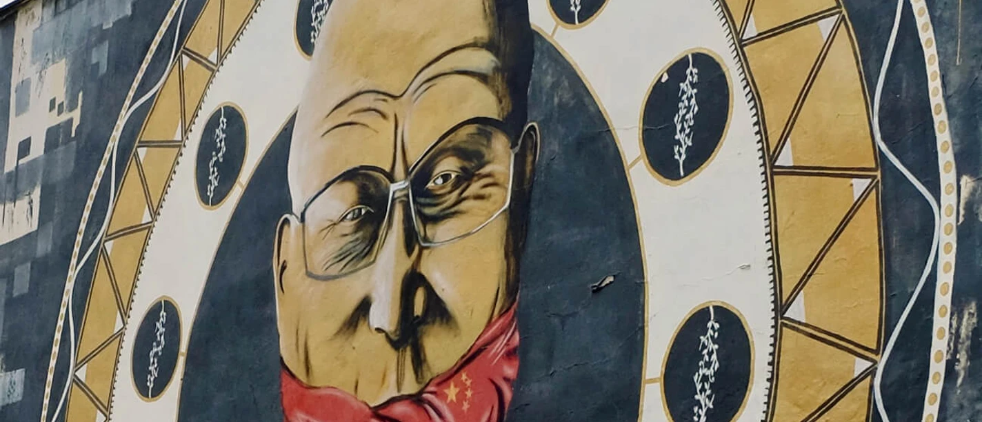 Mural A large mural shows an elderly man with glasses, his mouth covered by a red cloth, framed in a stylized patterned circle.