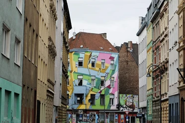 Mural Bunt bemaltes Gebäude an der Zülpicher Straße in Köln, mit geometrischen Formen in Pastellfarben auf der Fassade.